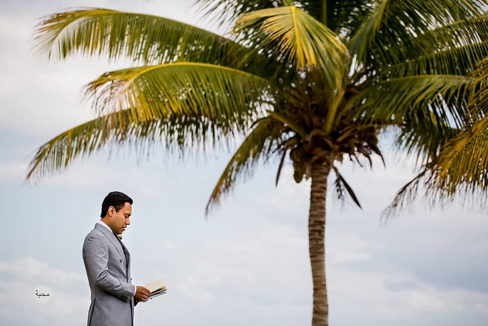  Groom sitting under a palm tree in Mexico