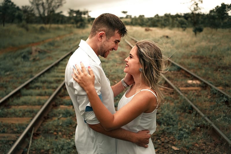 Man and woman on train tracks hugging