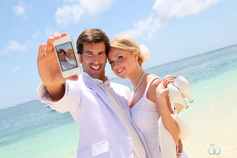 bride and groom on beach taking selfie