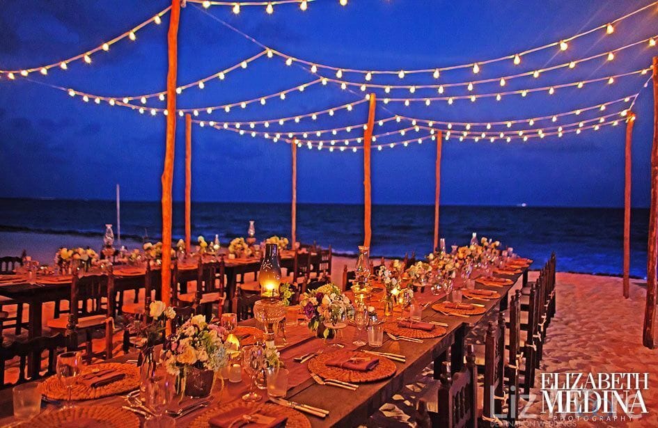 destination wedding reception on the beach with tiki lights and flower decor on tables